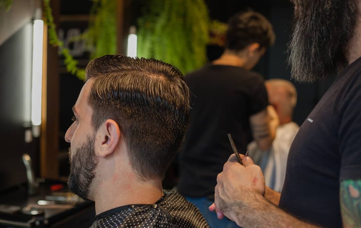 Barbeiro finalizando o corte de um cliente